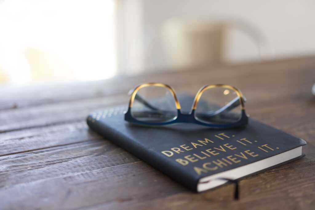 Photograph of a book on a table with the words, "dream it, believe it, achieve it." Achieve Goals