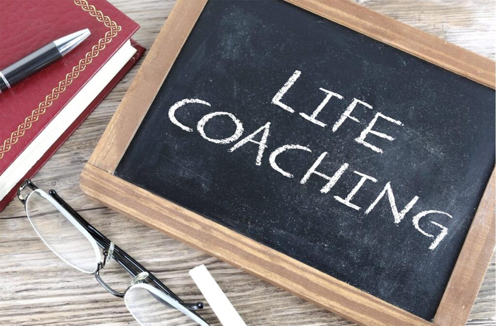 Chalk board on a table with the words Life Coaching written on it.