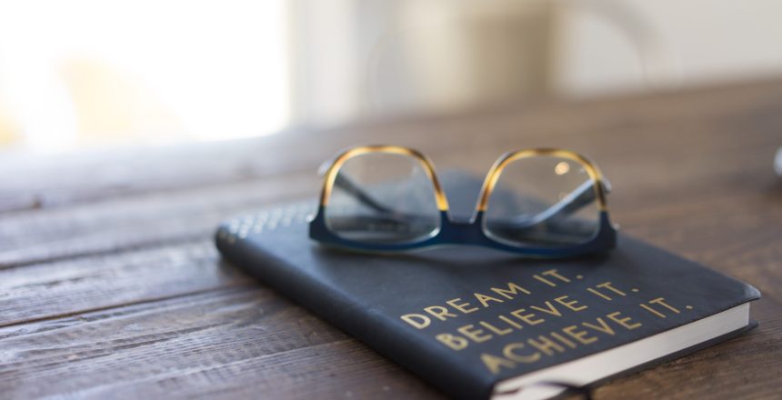 Photograph of a book on a table with the words, "dream it, believe it, achieve it." Achieve Goals
