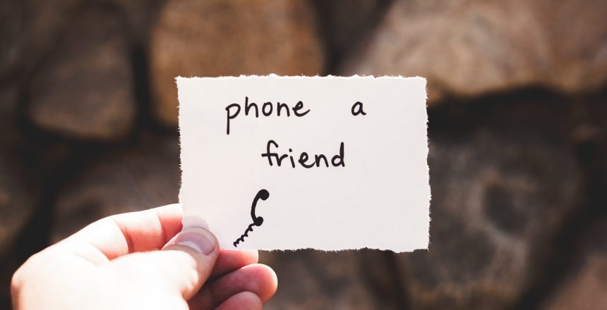 Image of a piece of paper in a person's hand with the words phone a friend.